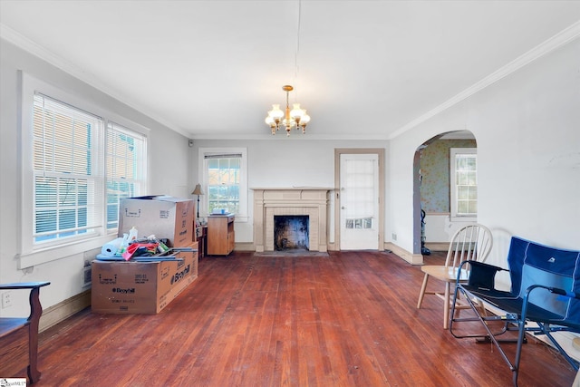 living room with ornamental molding, arched walkways, a brick fireplace, and wood finished floors