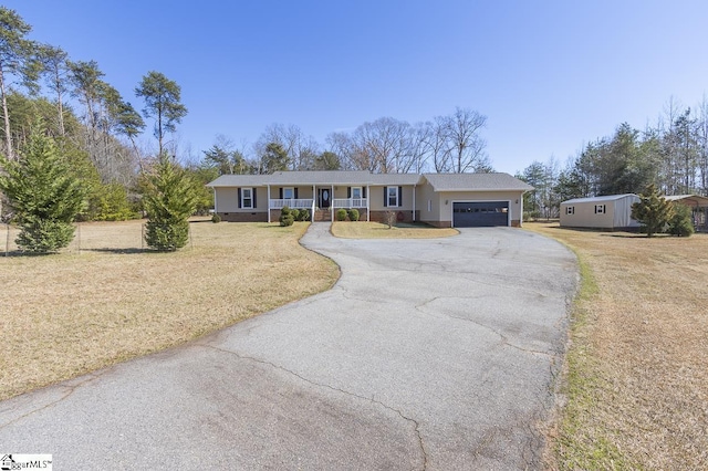 ranch-style house featuring a porch, a front lawn, a garage, and aphalt driveway