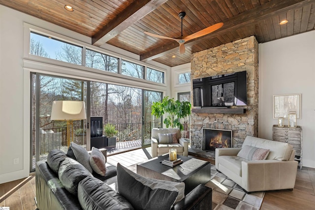 living area with a fireplace, wood finished floors, wood ceiling, baseboards, and beam ceiling