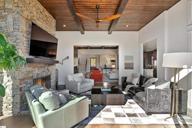 living room with a stone fireplace, wood finished floors, wood ceiling, stairway, and beam ceiling