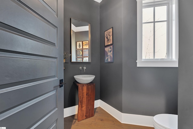 bathroom featuring toilet, a sink, baseboards, and wood finished floors