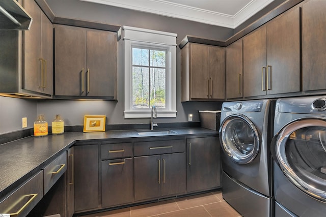 laundry area with cabinet space, ornamental molding, washing machine and dryer, a sink, and tile patterned floors