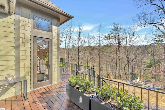 deck with a fire pit and a view of trees