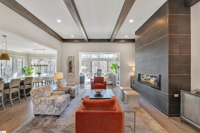 living area featuring recessed lighting, beam ceiling, a tiled fireplace, and wood finished floors