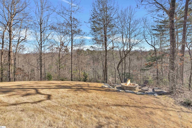 view of yard featuring a fire pit and a wooded view