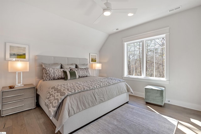 bedroom with baseboards, visible vents, ceiling fan, wood finished floors, and vaulted ceiling