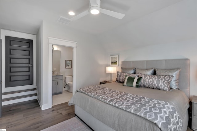 bedroom with visible vents, ceiling fan, ensuite bath, wood finished floors, and vaulted ceiling