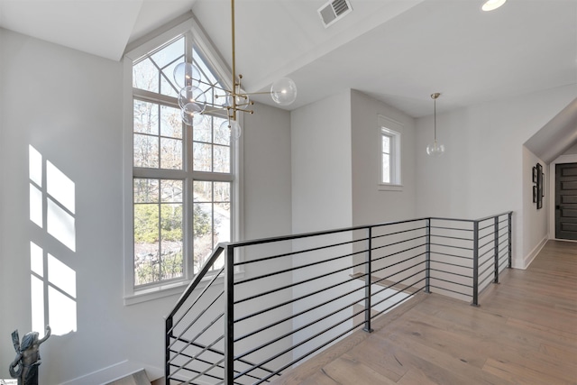 hallway featuring a chandelier, a healthy amount of sunlight, visible vents, and an upstairs landing