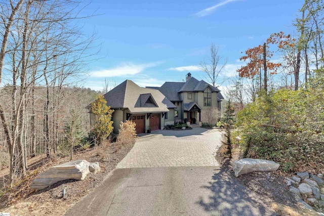 view of front facade featuring decorative driveway and a chimney