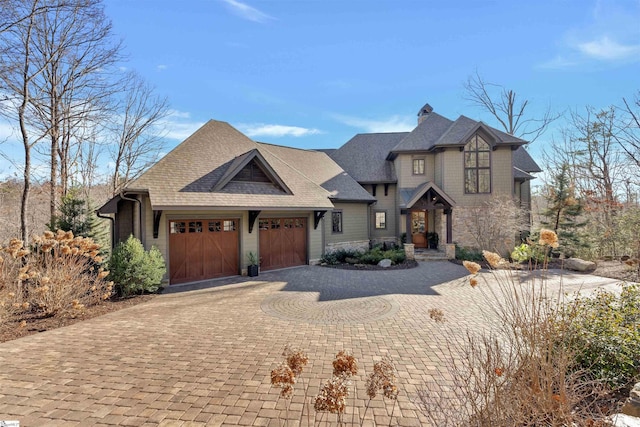 view of front facade featuring a shingled roof, decorative driveway, and an attached garage