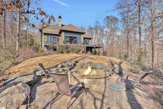 rear view of house with a patio, an outdoor fire pit, a chimney, and a wooden deck