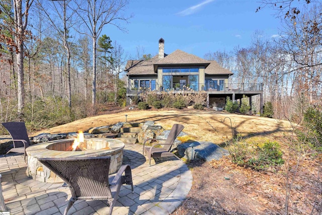 back of house featuring a deck, a chimney, a patio, and a fire pit