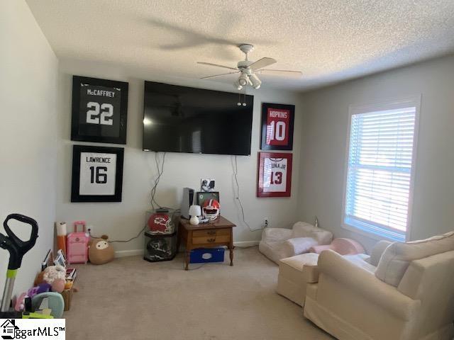 living room featuring ceiling fan, a textured ceiling, carpet flooring, and baseboards