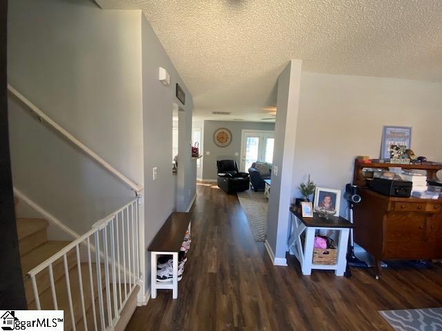 hallway with a textured ceiling, stairs, baseboards, and wood finished floors