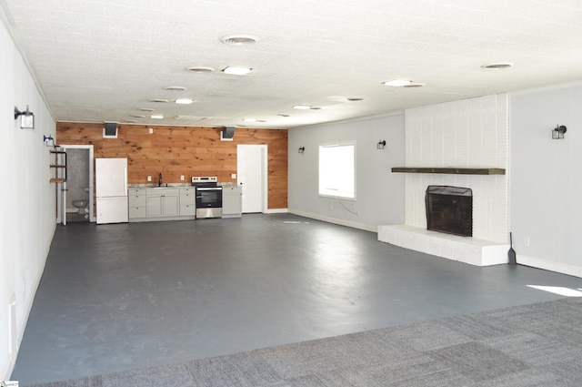 612 W Main St, Easley, SC 29640 - unfurnished living room with wooden walls, baseboards, finished concrete floors, a brick fireplace, and a sink