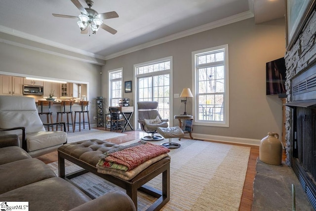 living area featuring ornamental molding, ceiling fan, baseboards, and wood finished floors