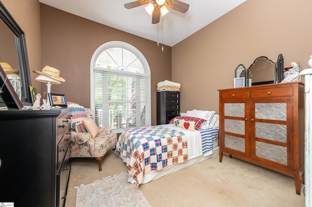 bedroom with lofted ceiling, a ceiling fan, and light colored carpet