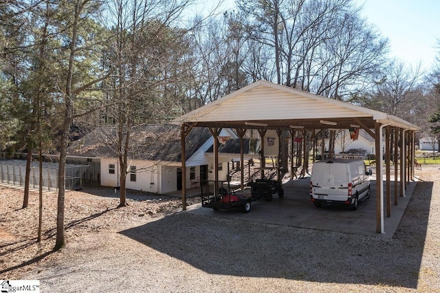 view of parking with a detached carport, fence, and driveway