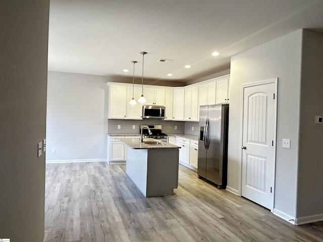 kitchen featuring a sink, visible vents, appliances with stainless steel finishes, light wood-type flooring, and tasteful backsplash