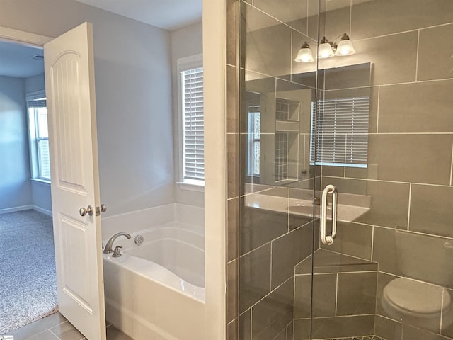 bathroom with a stall shower and a garden tub