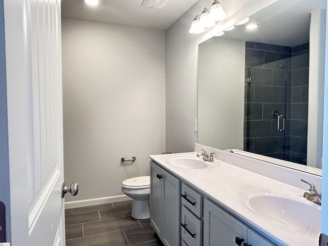 bathroom with double vanity, a stall shower, a sink, and toilet