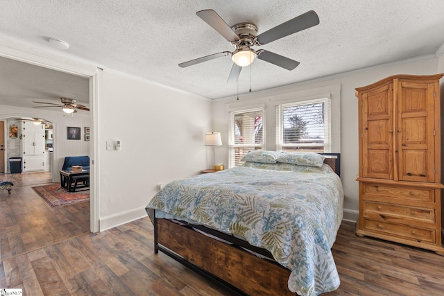 bedroom with a textured ceiling, ornamental molding, wood finished floors, and baseboards