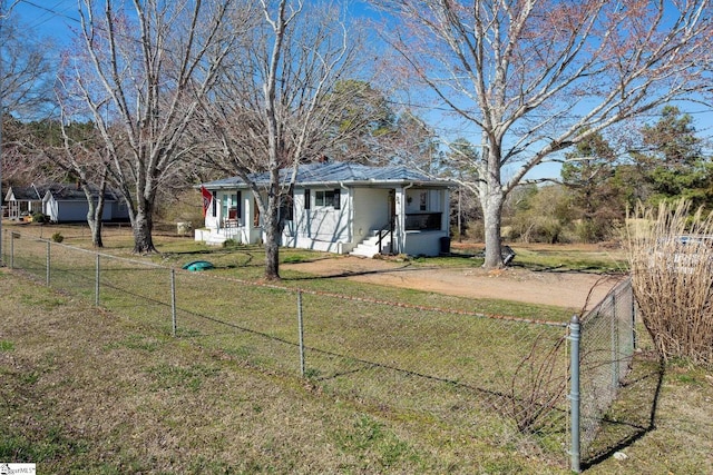 view of front of house with covered porch, a fenced front yard, dirt driveway, and a front lawn