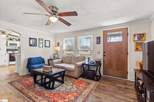 living area featuring arched walkways, a textured ceiling, wood finished floors, and crown molding