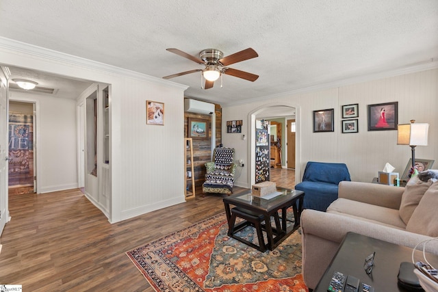 living room with arched walkways, a wall mounted AC, wood finished floors, and a textured ceiling