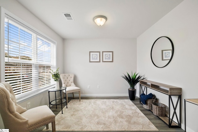 living area featuring visible vents, baseboards, and wood finished floors