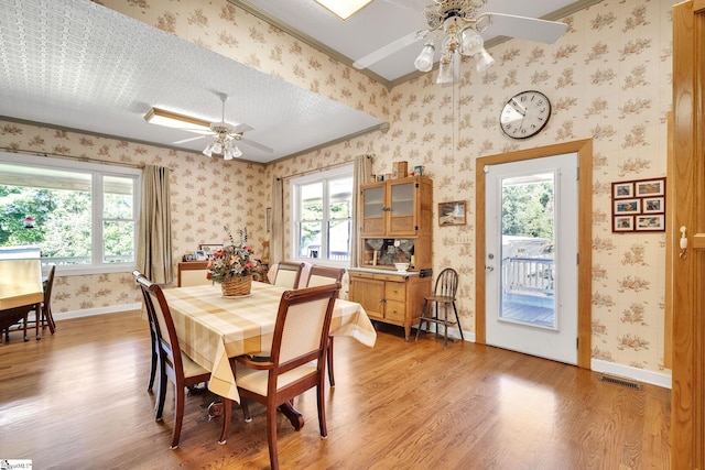 dining room with light wood-style floors, visible vents, baseboards, and wallpapered walls