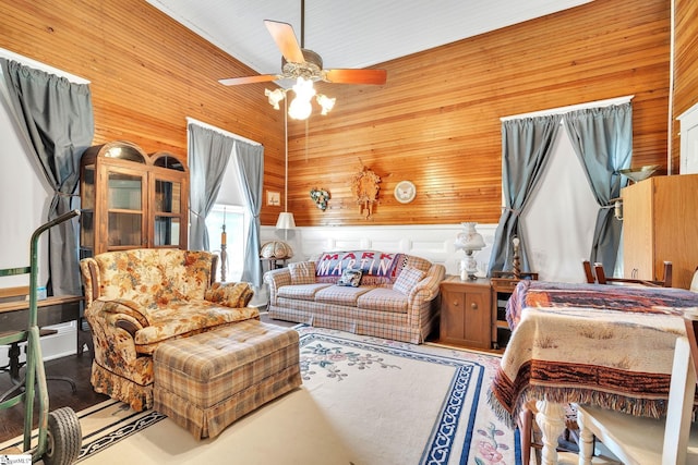 interior space with ceiling fan, wooden walls, and high vaulted ceiling