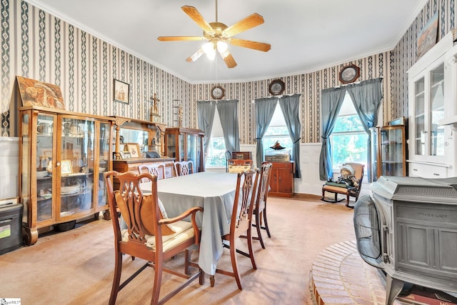 dining room with crown molding, light carpet, and wallpapered walls