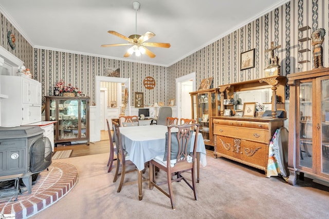 dining area featuring a wood stove, wallpapered walls, ceiling fan, and ornamental molding