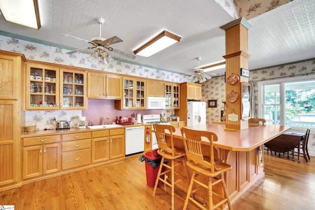 kitchen with wallpapered walls, white appliances, a ceiling fan, light countertops, and a sink