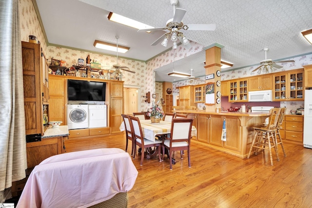 dining space with wallpapered walls, washing machine and dryer, a ceiling fan, and light wood-style floors