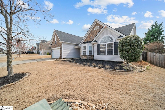 view of front of home featuring a garage, stone siding, fence, and concrete driveway