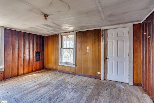 empty room with light wood finished floors and wood walls