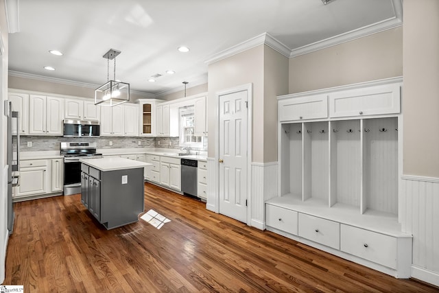 kitchen with a wainscoted wall, appliances with stainless steel finishes, a sink, and white cabinetry