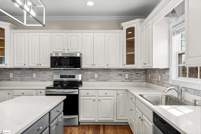 kitchen with decorative backsplash, ornamental molding, stainless steel appliances, white cabinetry, and a sink