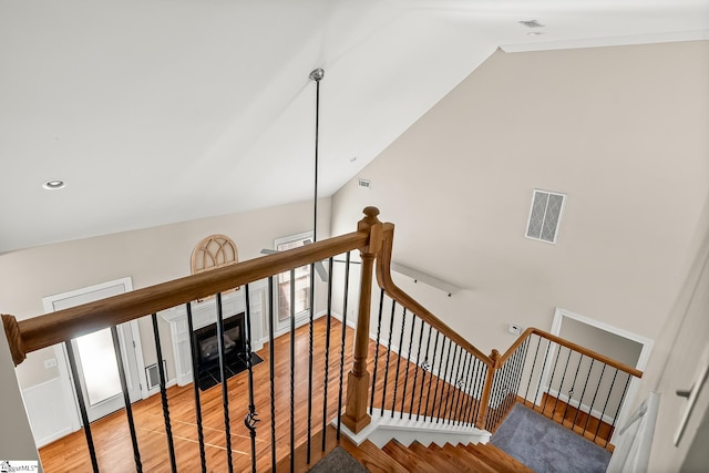 stairway featuring lofted ceiling, visible vents, baseboards, and wood finished floors