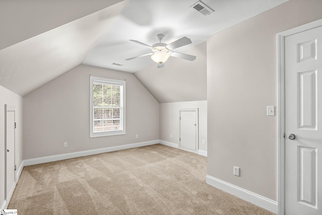 additional living space featuring light carpet, baseboards, visible vents, lofted ceiling, and ceiling fan