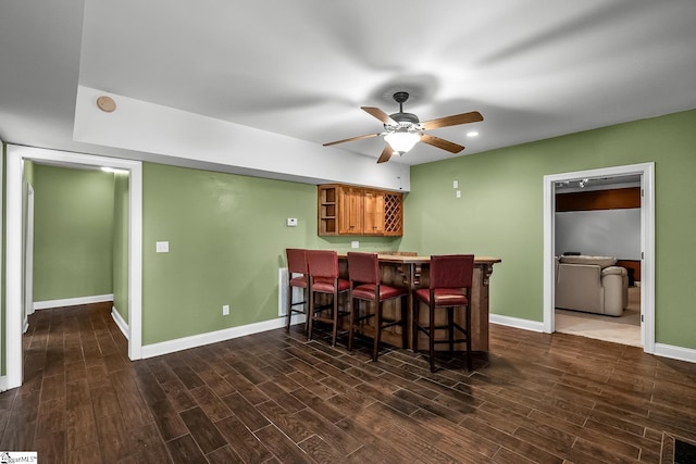 dining room with dark wood-style floors, baseboards, a ceiling fan, and bar