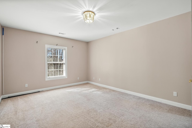 spare room with baseboards, visible vents, and light colored carpet