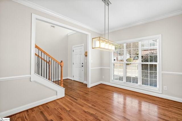 unfurnished dining area with stairs, baseboards, wood finished floors, and crown molding