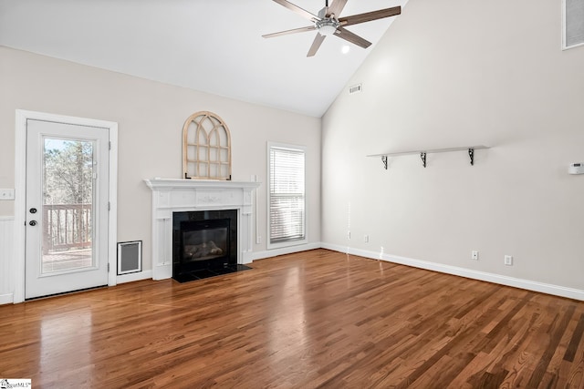 unfurnished living room featuring ceiling fan, high vaulted ceiling, a tile fireplace, wood finished floors, and visible vents