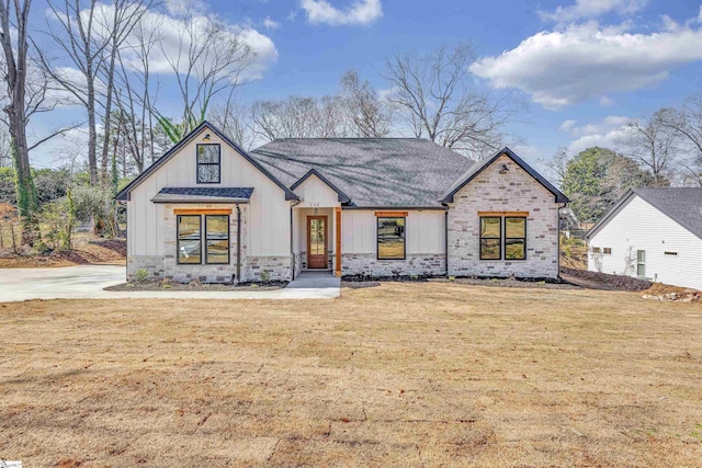 modern farmhouse style home with stone siding, a front lawn, and board and batten siding