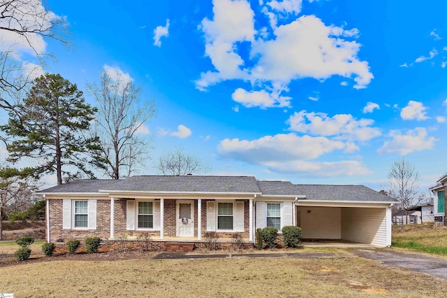 single story home featuring brick siding, dirt driveway, a porch, a carport, and a front yard