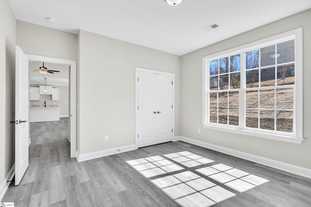 unfurnished bedroom with a closet, visible vents, baseboards, and wood finished floors