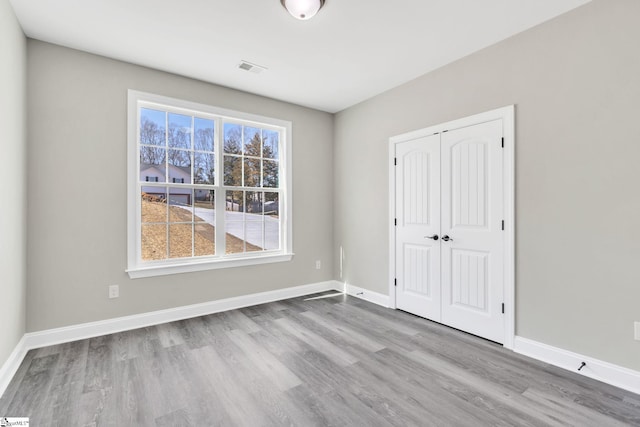 unfurnished bedroom featuring a closet, baseboards, and wood finished floors